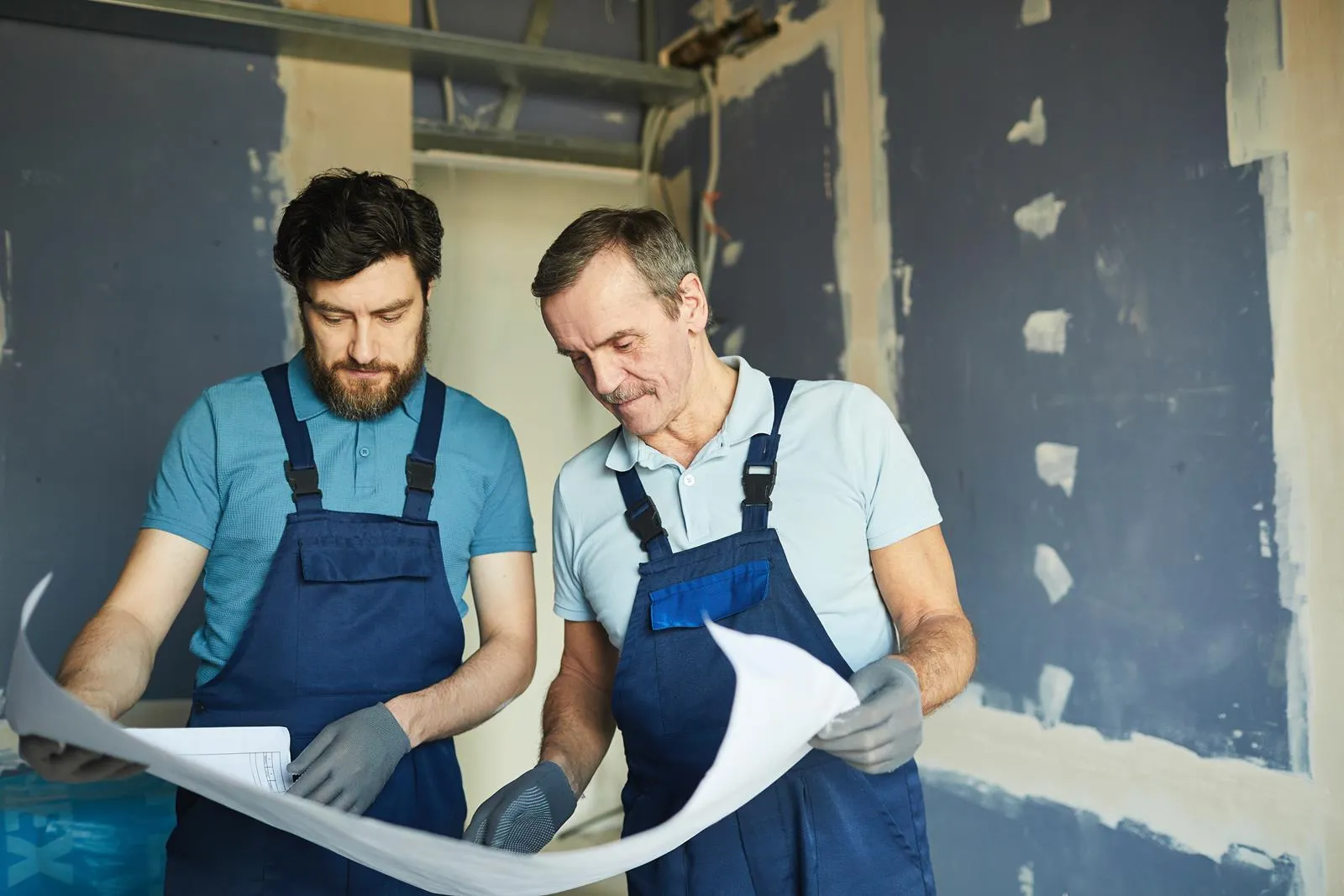 Zwei Trockenbauer besprechen einen Bauplan auf der Baustelle